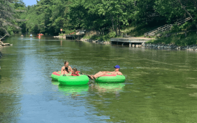Three people floating down the Platte River in green tubes on a sunny day.